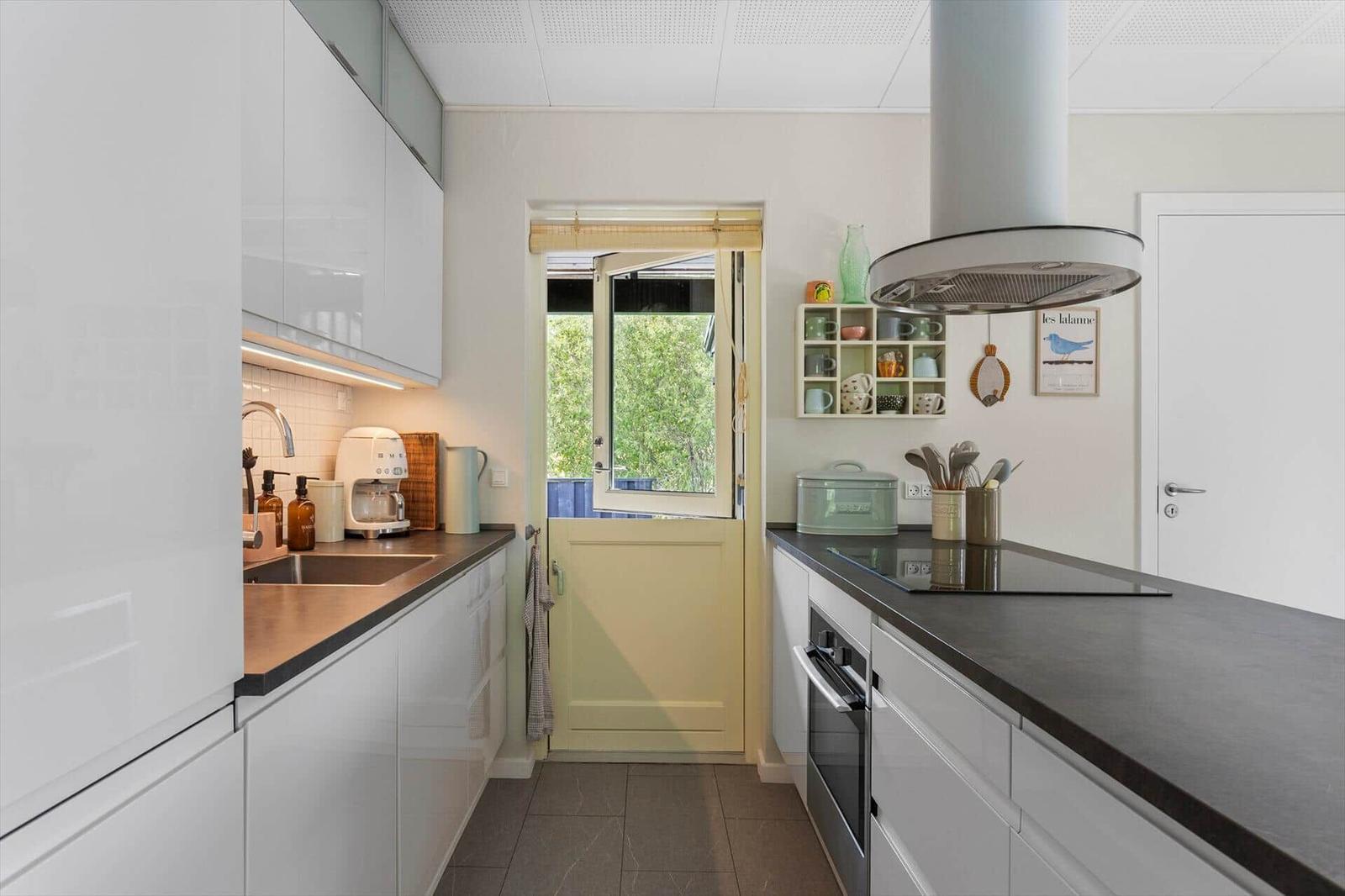 Kitchen with white cabinets, dark countertop, and window to the garden.