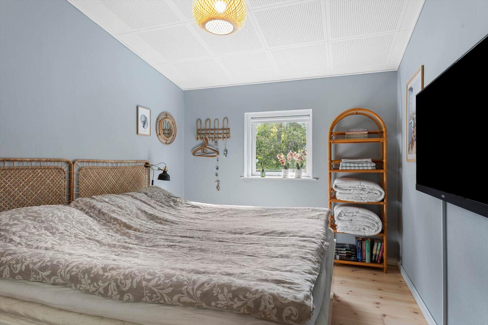 Bedroom with bed, window, bookshelf, and TV.