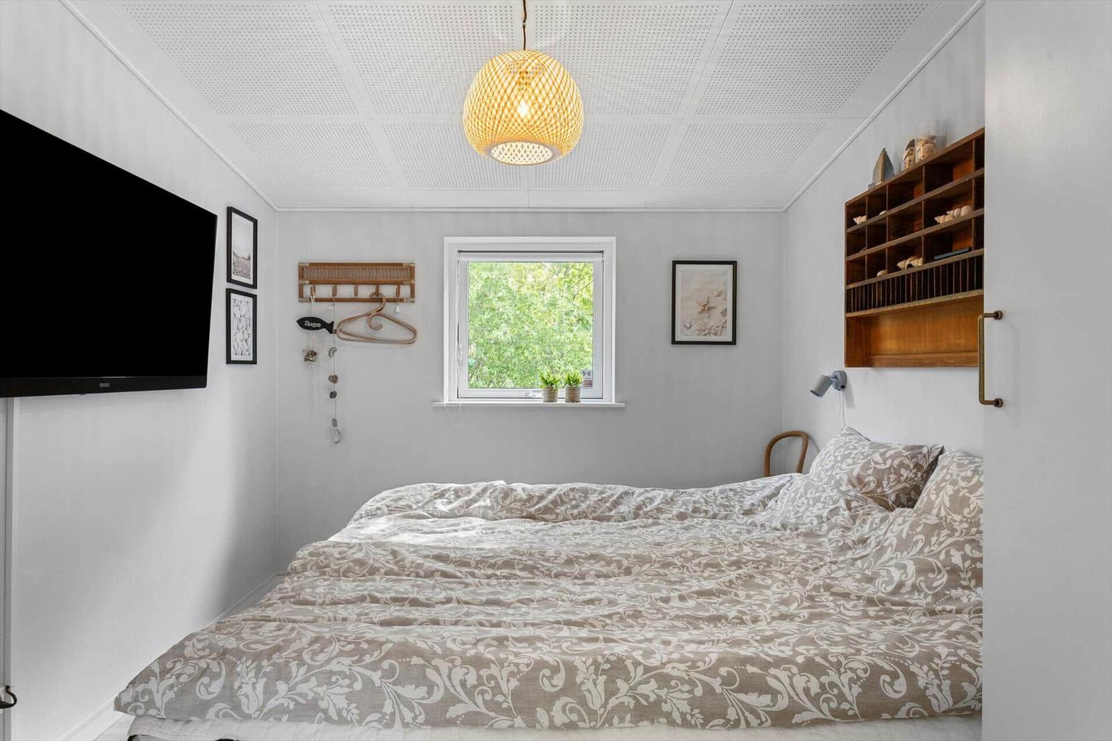 Bedroom with bed, window, wall shelf, and ceiling light.