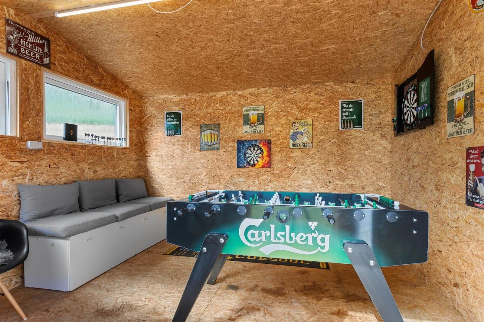 Room with foosball table, sofa, and wall decorations made of wood.