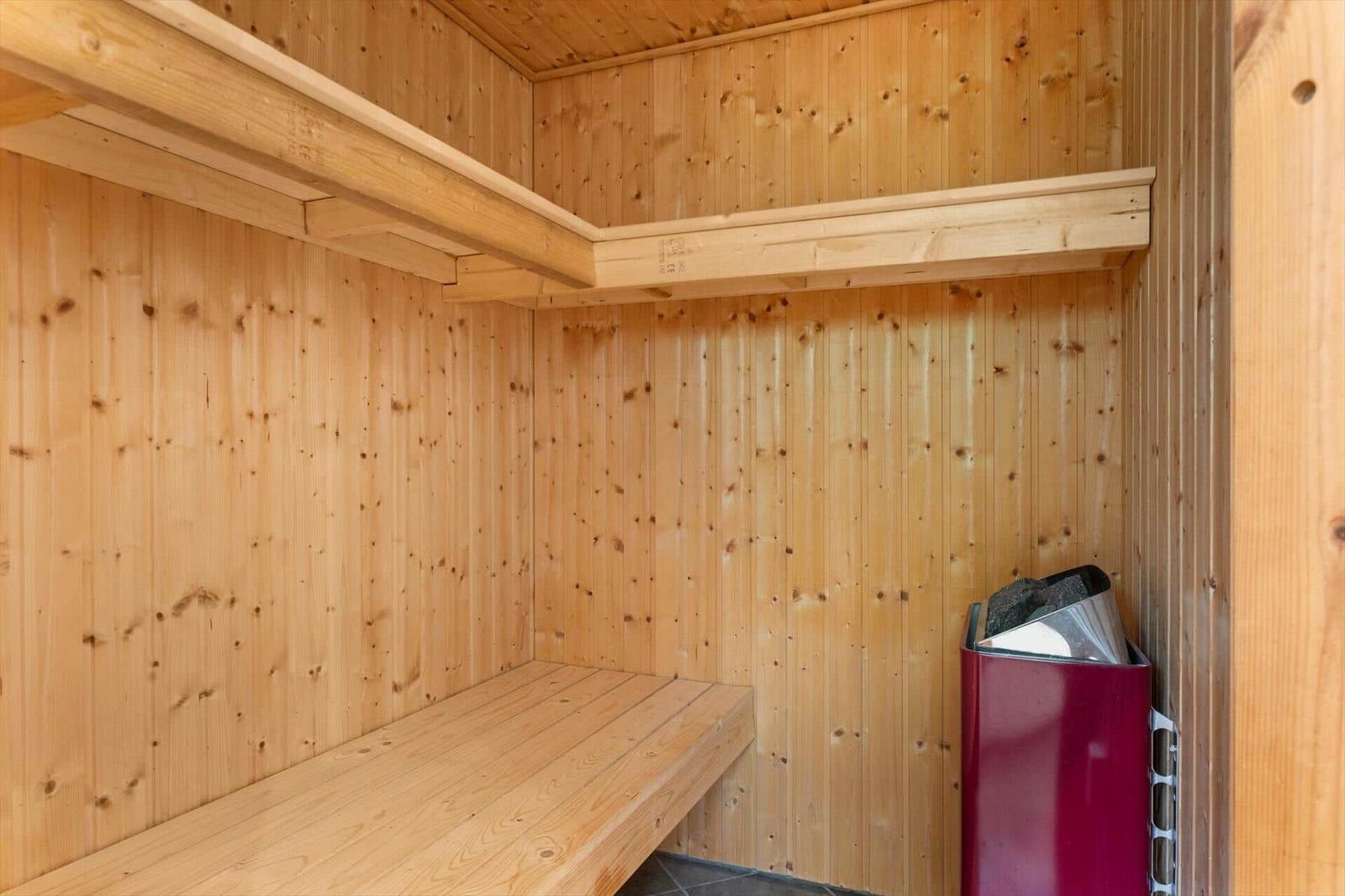 Sauna with wooden cladding, bench, and heater.