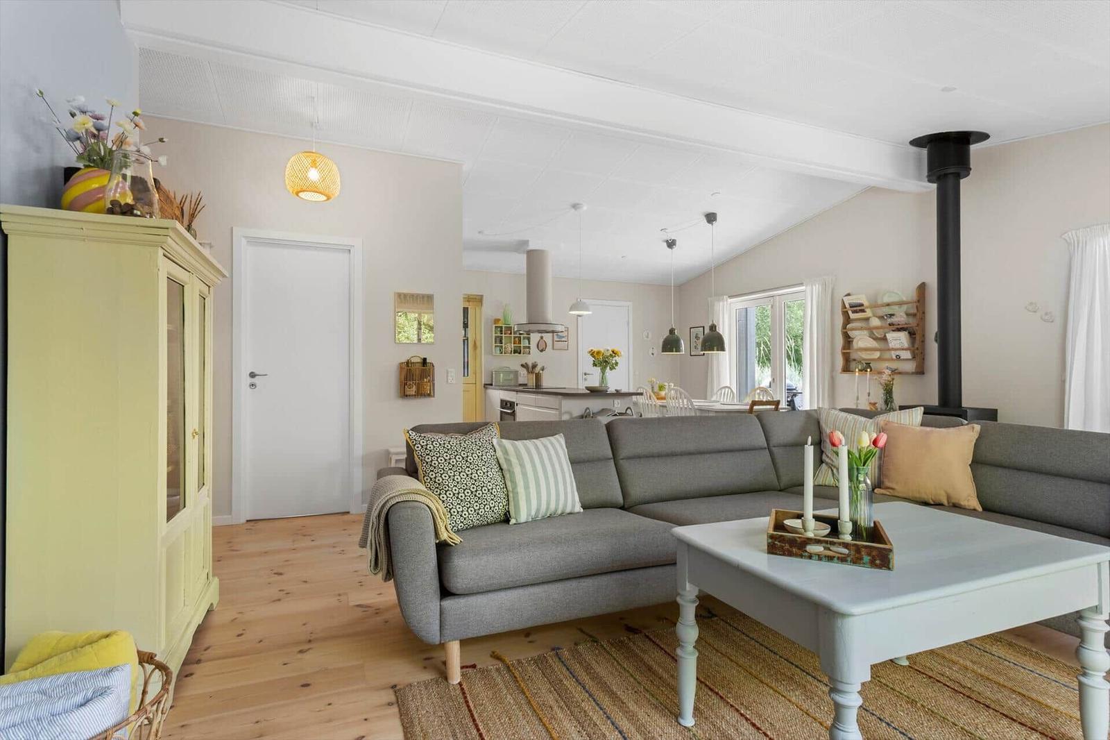 Living room with gray sofa, wooden floor, and dining area in the background.