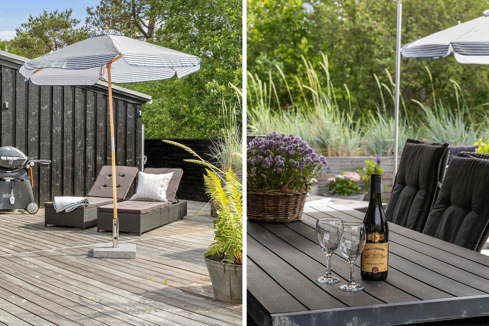 Deck with loungers, umbrella, and grill. Table with wine and flowers.