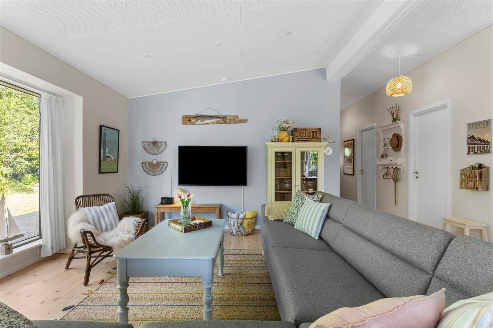 Living room with sofa, coffee table, and TV. Window with view of garden.
