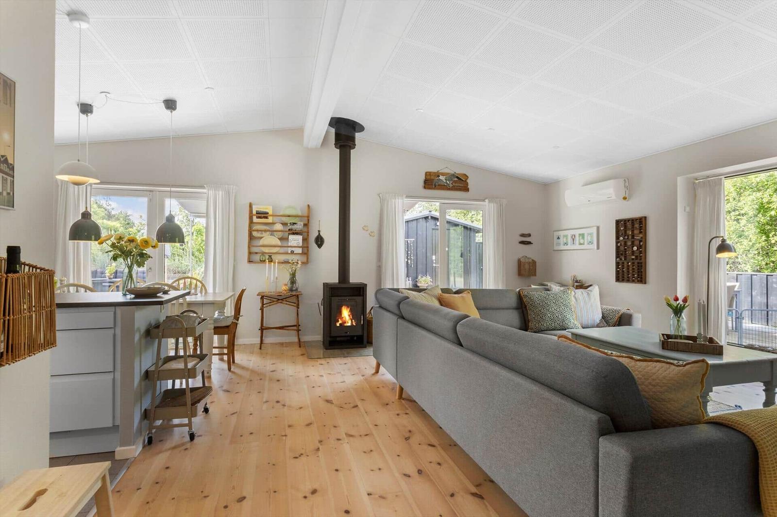 Living and dining area with wooden floor, fireplace, and large windows.