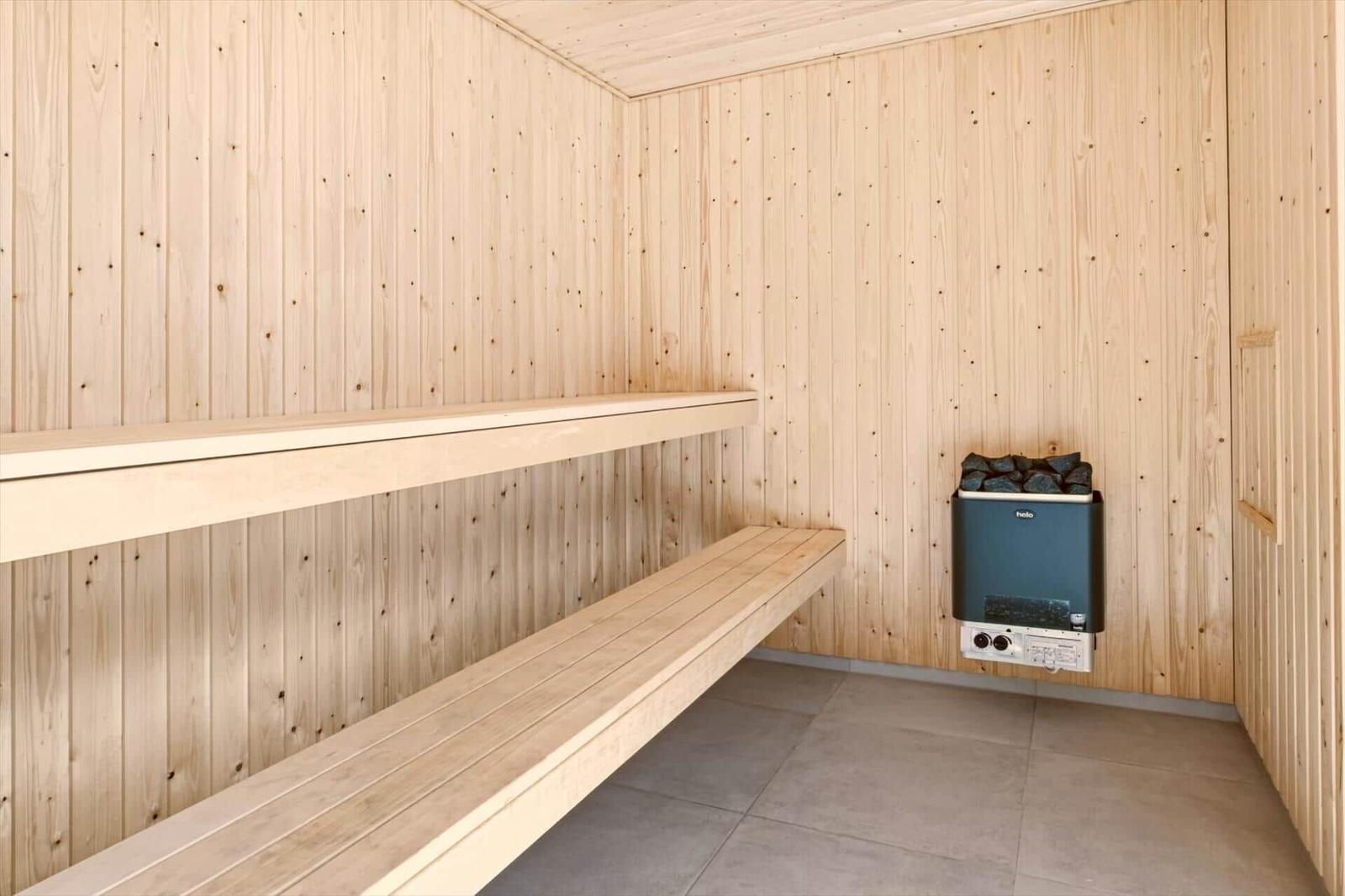 Sauna mit Holzwand und Sitzbänken, Heizung mit Steinen an der Wand.