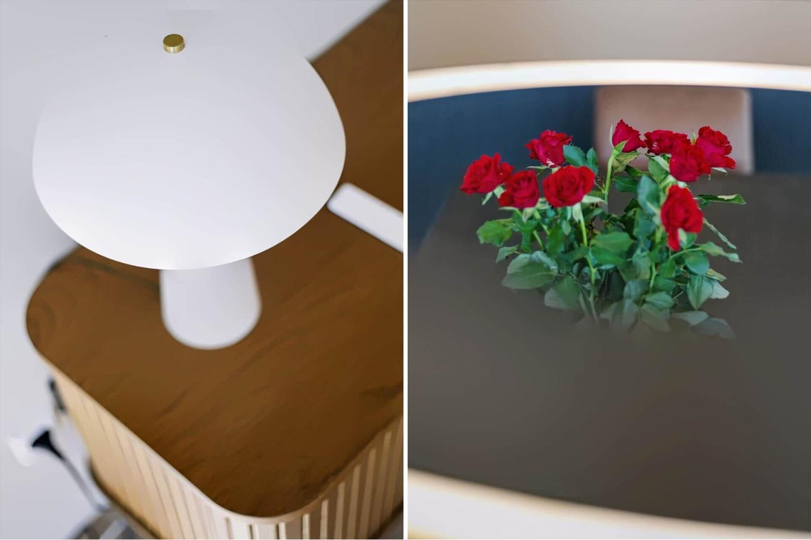 Weiße Lampe auf Holzoberfläche. Rote Rosen auf dunkler Tischplatte.