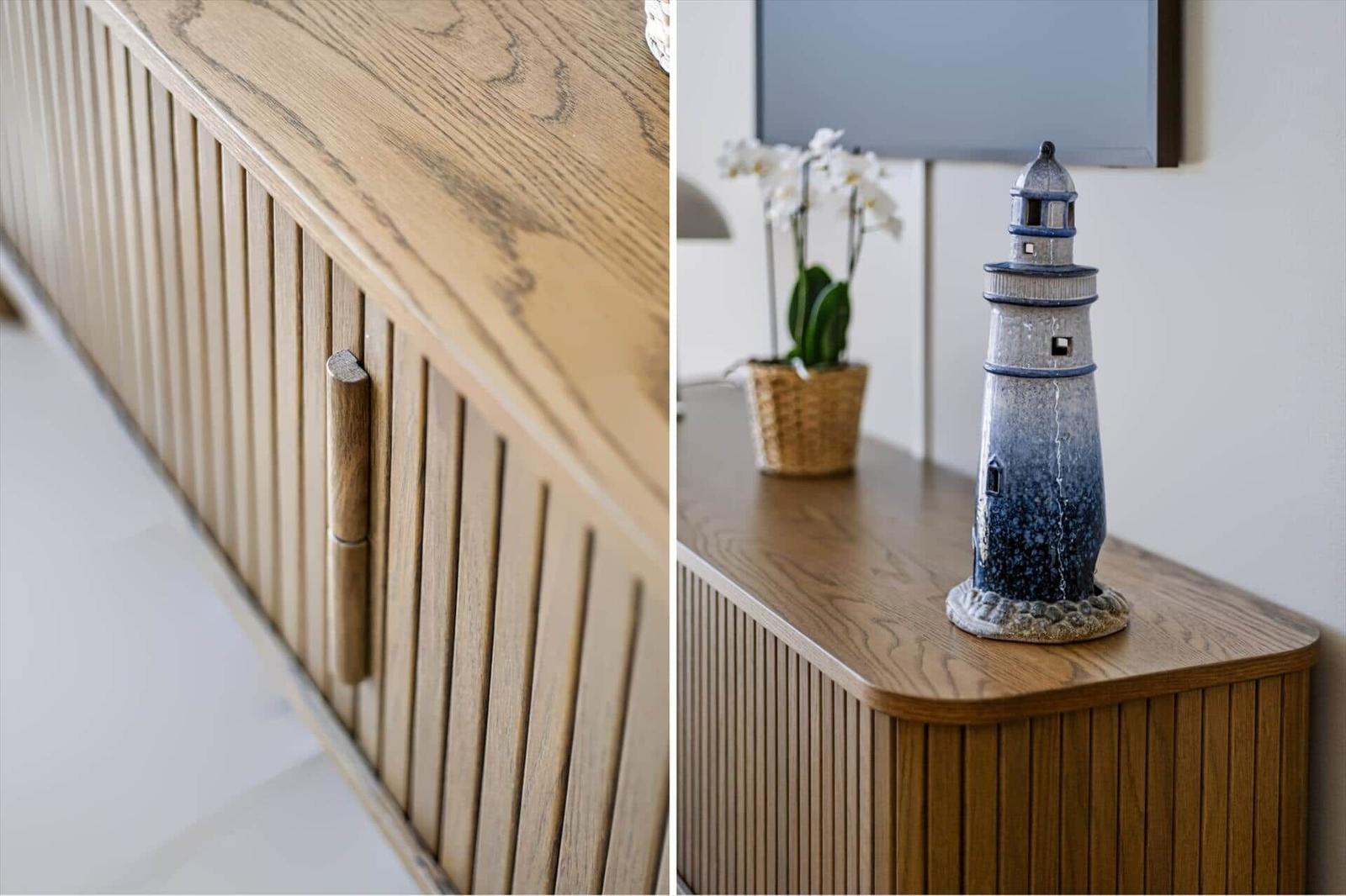 Holzschrank mit vertikalen Paneelen und einer Holztürgriff. Auf dem Schrank steht eine Laterne und eine Orchidee.