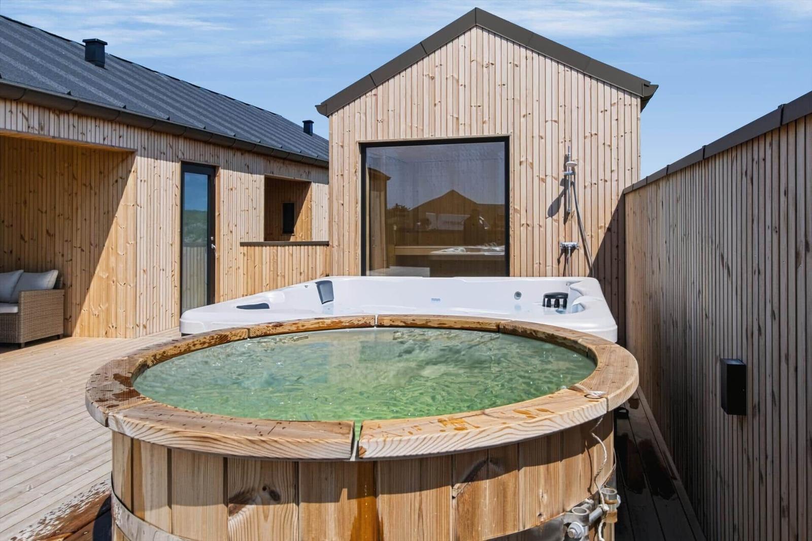 Haus mit Holzverkleidung, Whirlpool und Holzbadewanne auf Terrasse.