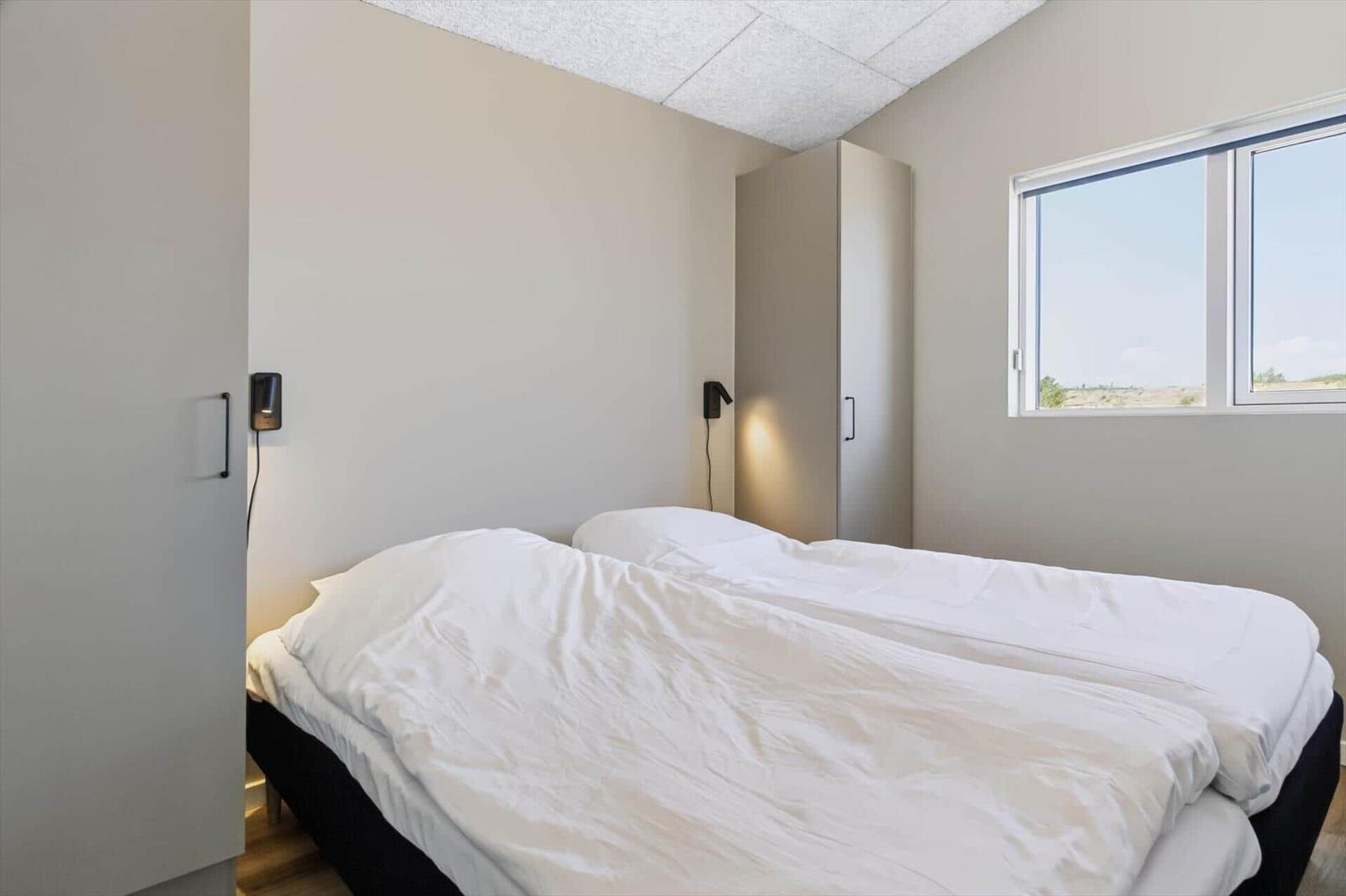 Ein Schlafzimmer mit einem Doppelbett, einem Fenster und einer Garderobe.