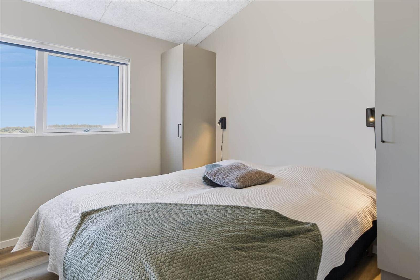 Schlafzimmer mit Bett, Fenster und Schrank. Blick auf den Himmel.