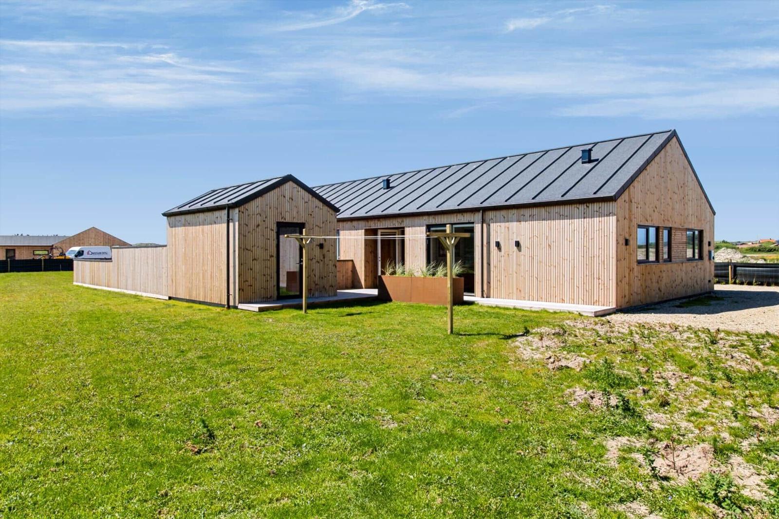Moderne Holzhütte mit grauem Dach und großem Garten