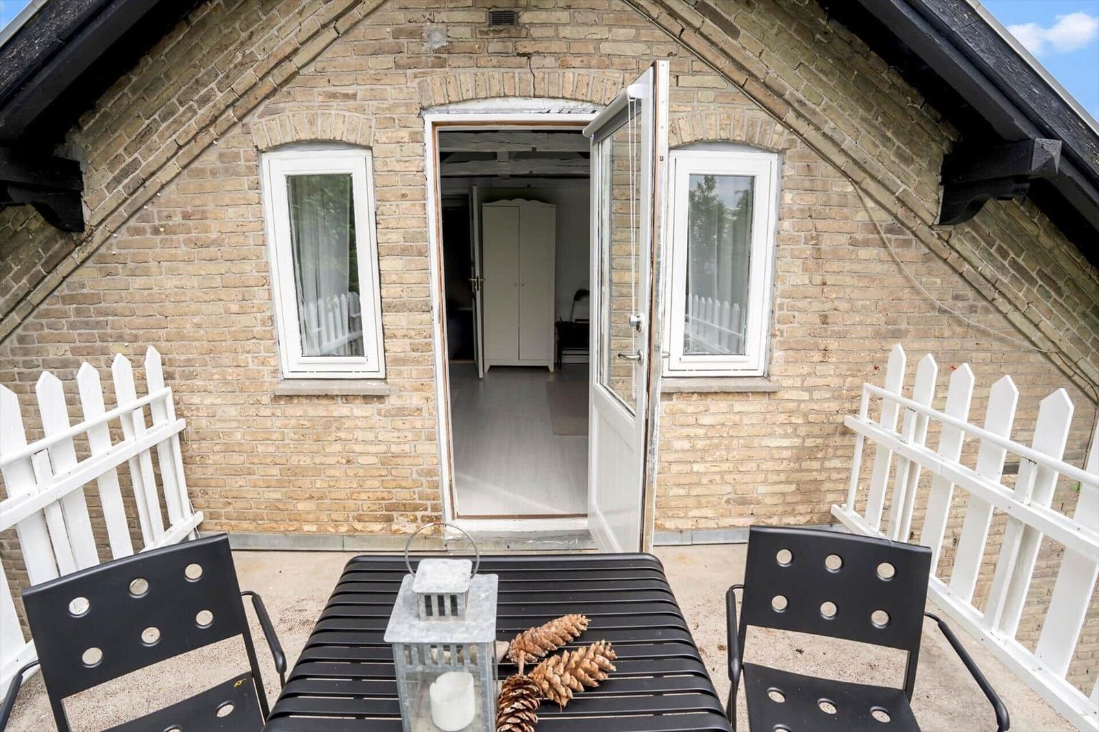 Terrasse mit Tisch und Stühlen vor einem Steinhaus mit offener Tür.