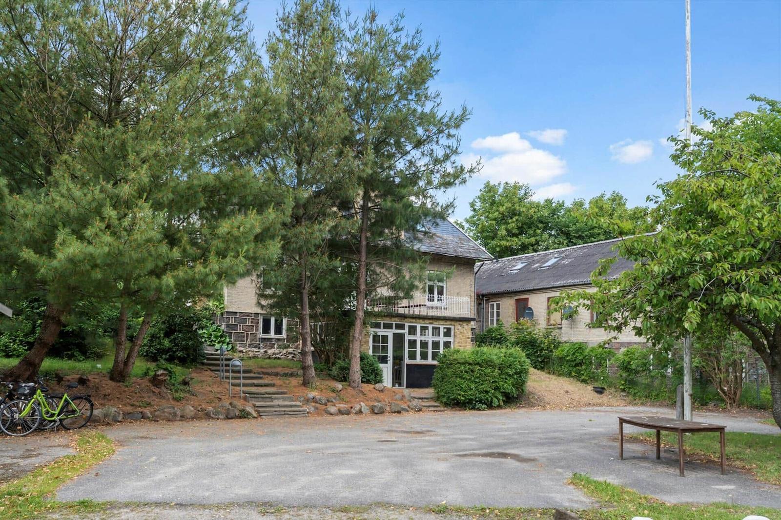 Haus mit Garten, Parkplatz und Fahrrädern unter Bäumen.