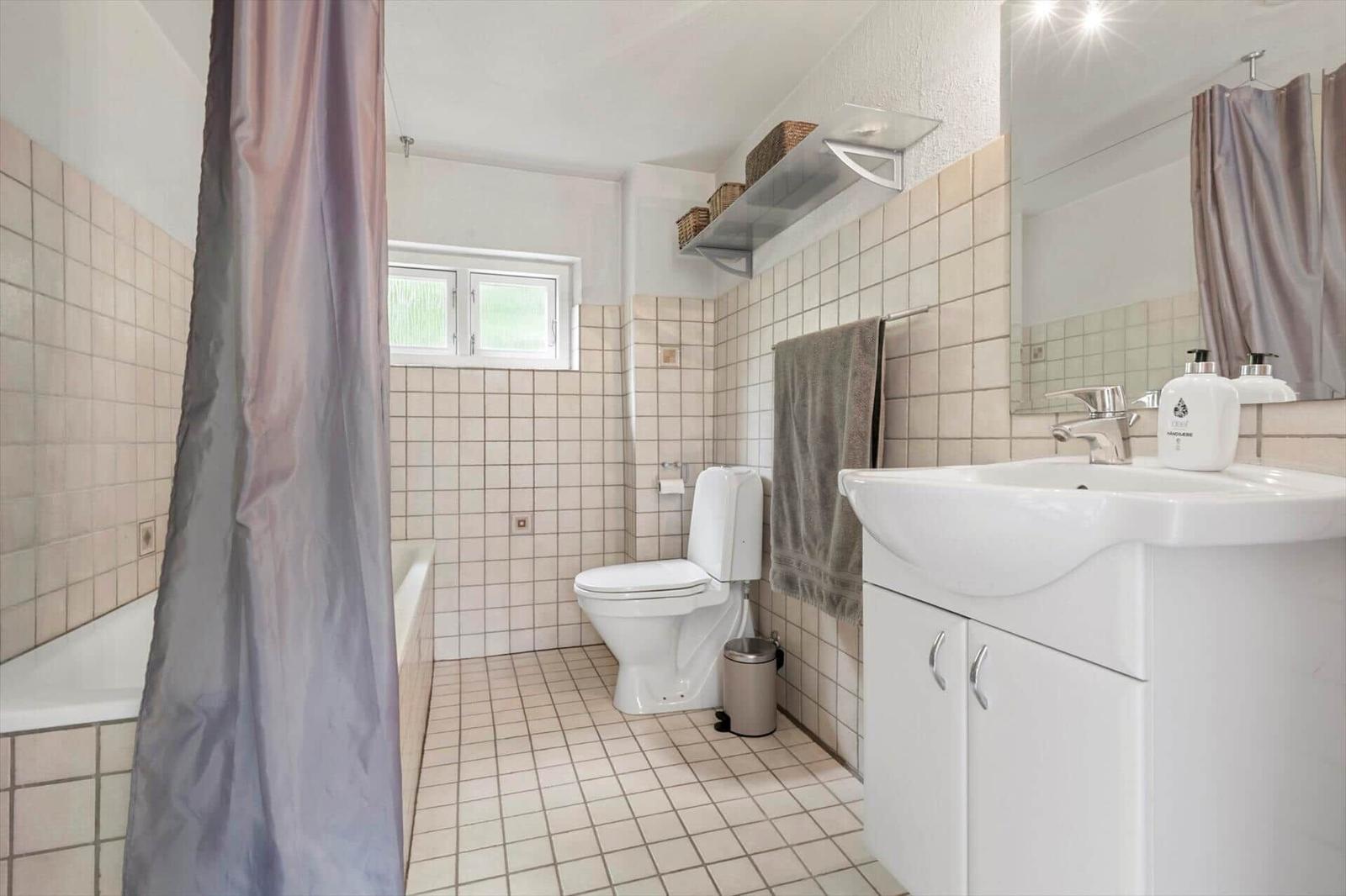 Badezimmer mit Badewanne, Toilette und Waschbecken mit Spiegel.