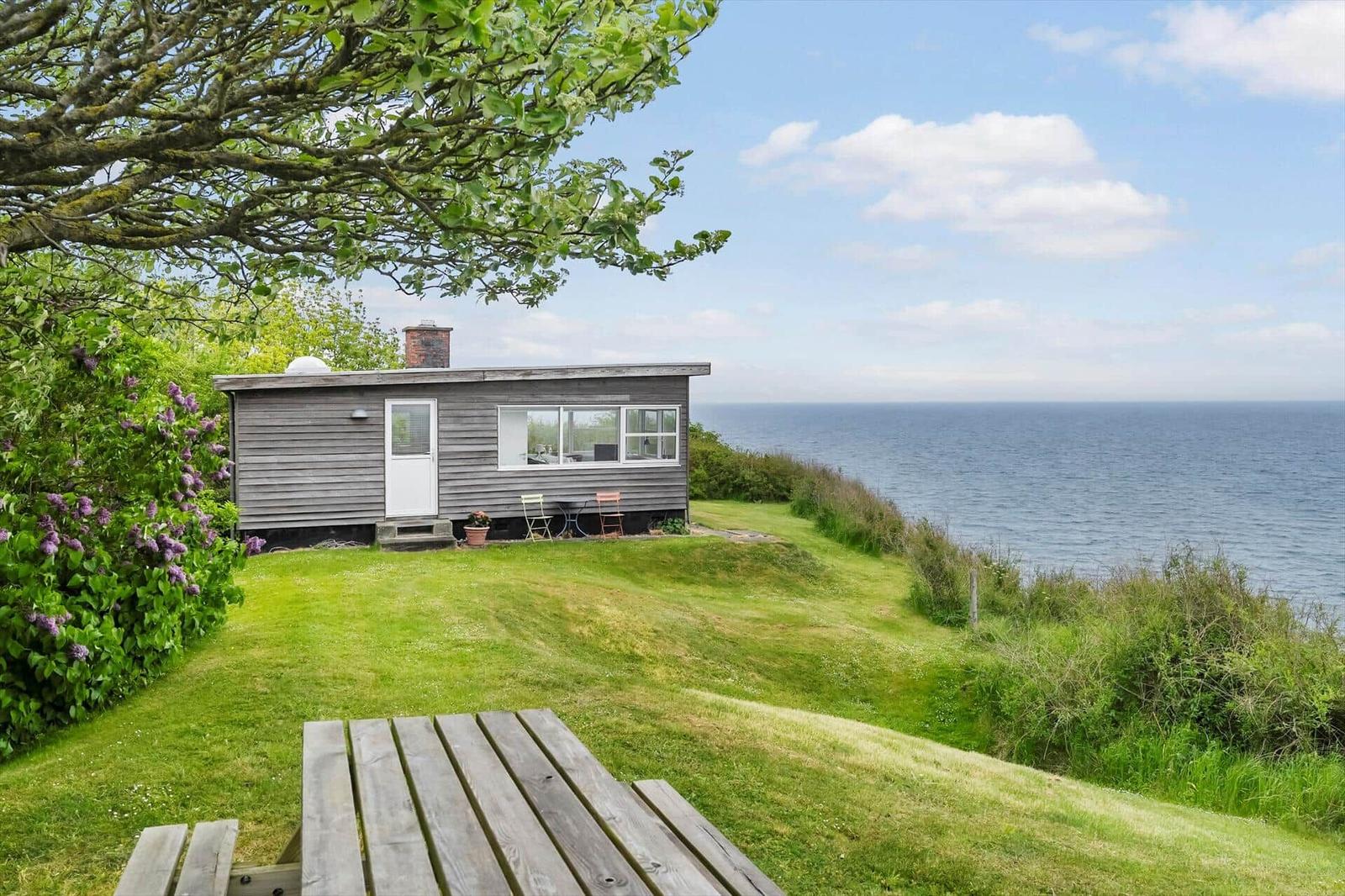 Kleines Haus mit Meerblick, Garten und Holztisch. Blick auf das Meer.