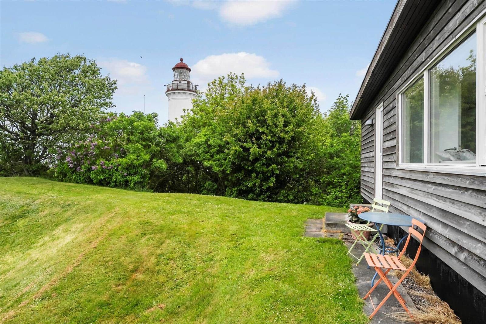 Haus mit Terrasse, Garten und Blick auf Leuchtturm.