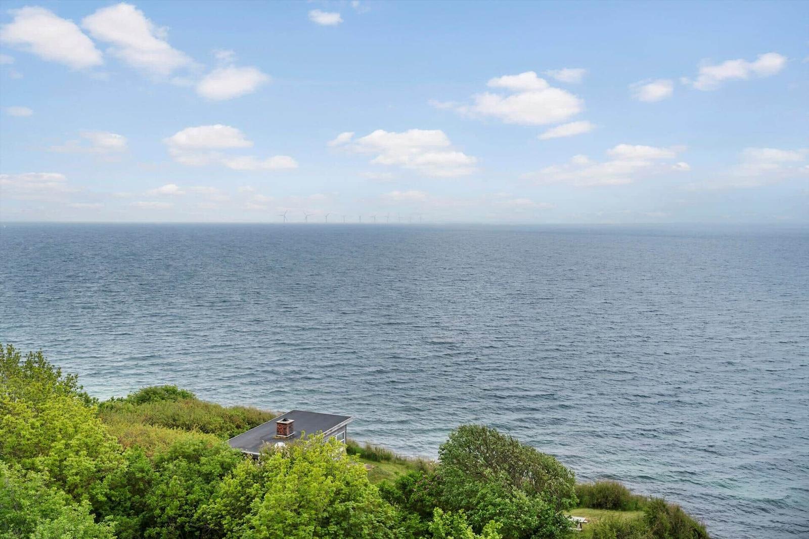 Haus am Meer mit Blick auf Windkraftanlagen