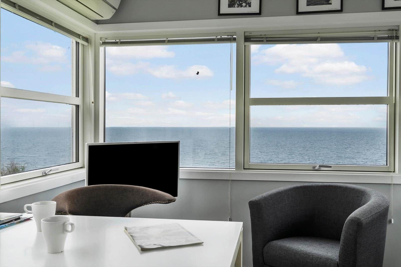 Raum mit Blick auf Meer, Tisch, Stühle und Fenster