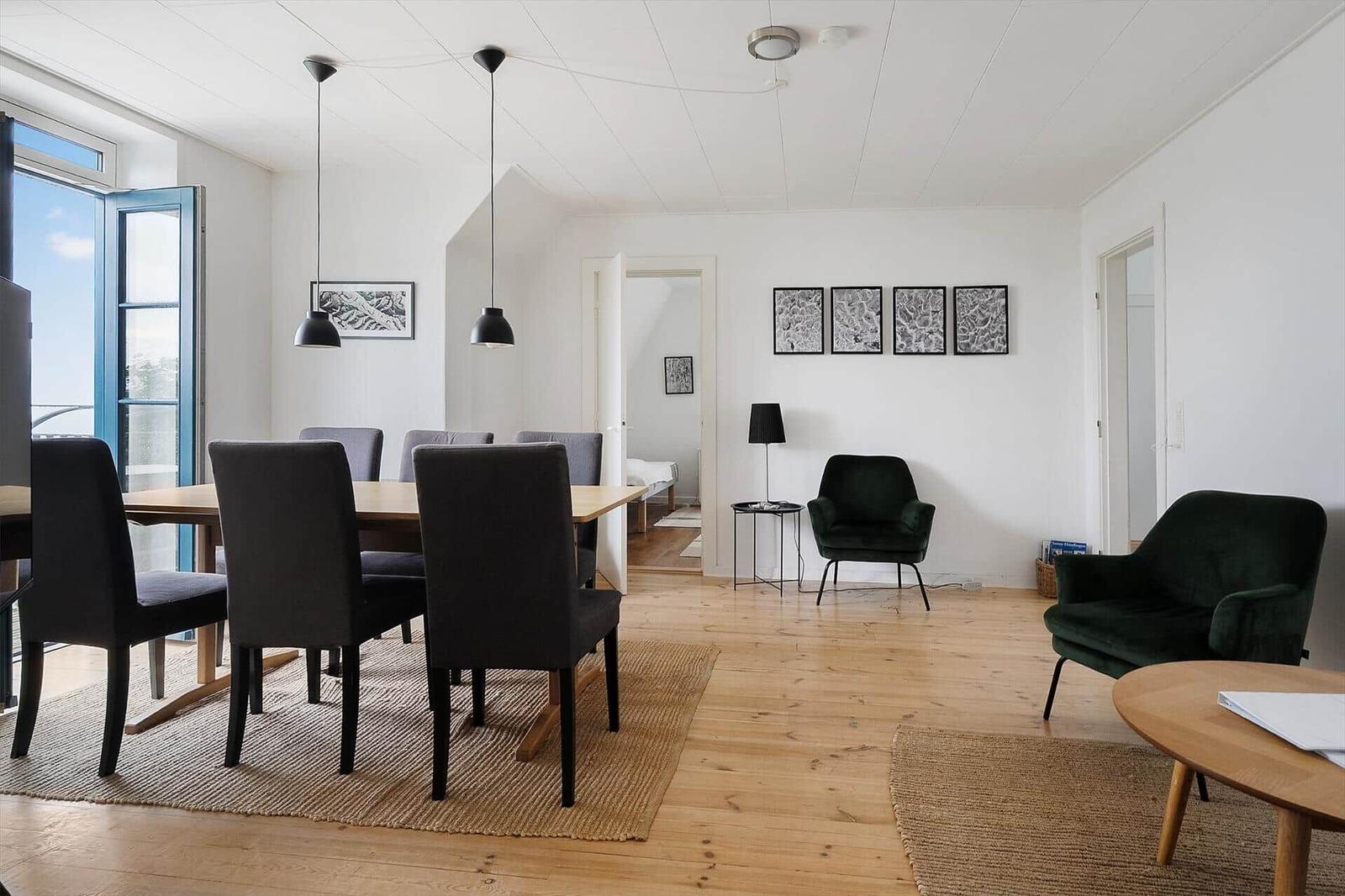 Essbereich mit Tisch und Stühlen, Wohnbereich mit zwei Sesseln und Holzboden.