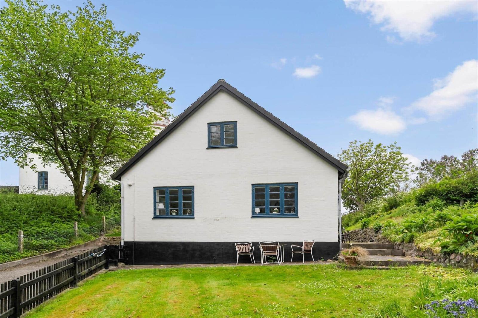 Ein weißes Haus mit blauen Fenstern und einem Garten mit Stufen.