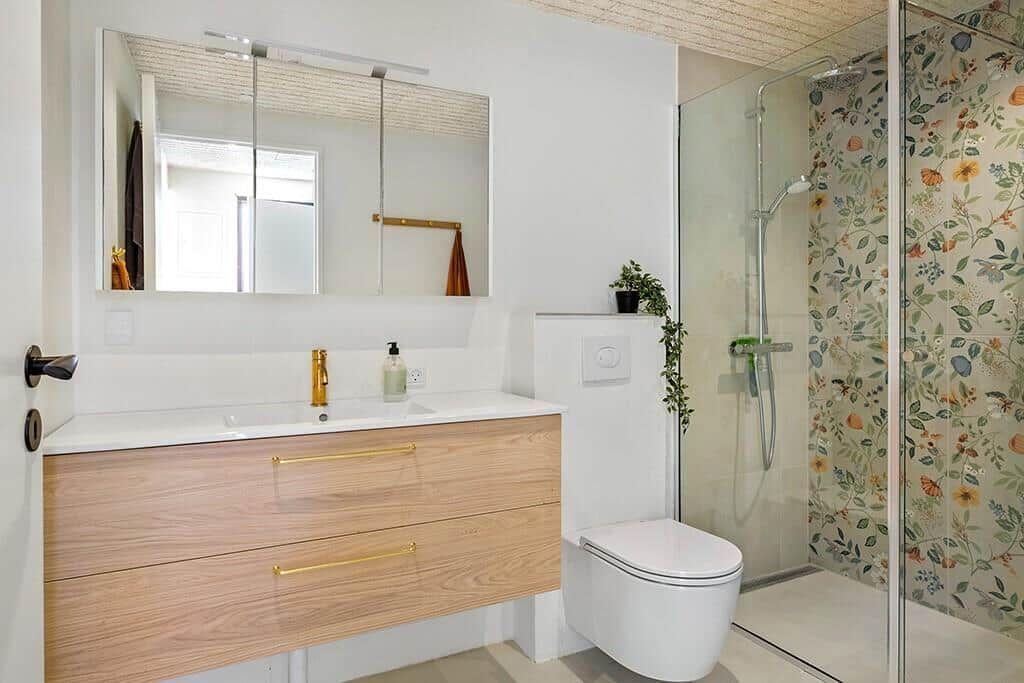 Bad mit Waschbecken, Spiegelschrank, Dusche und Toilette.