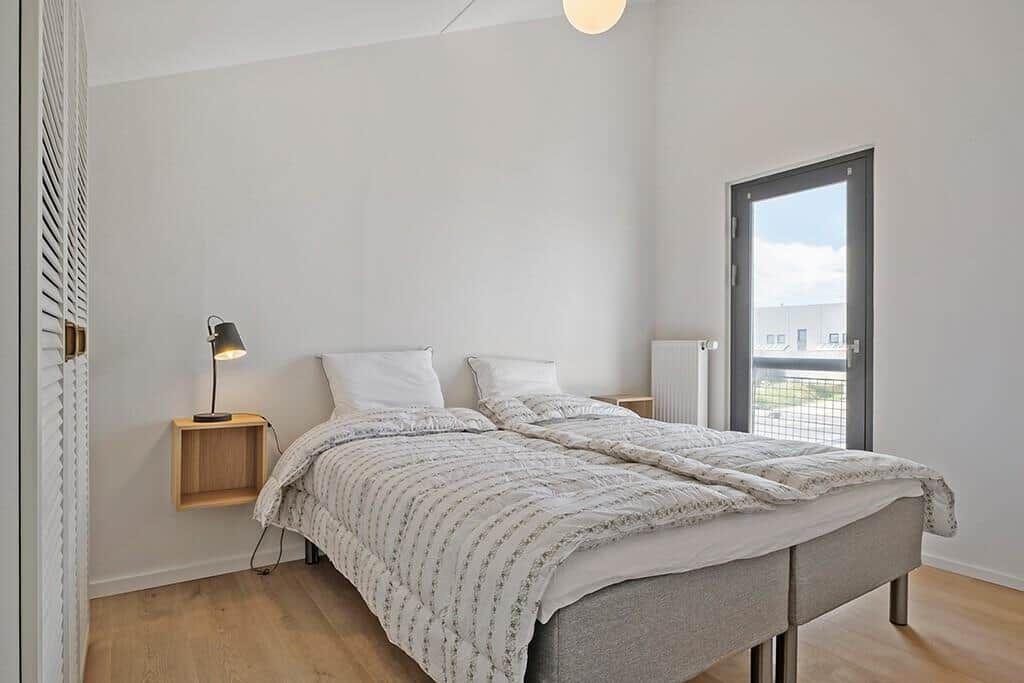 Schlafzimmer mit Doppelbett, Nachttisch und Fenster zur Aussicht.
