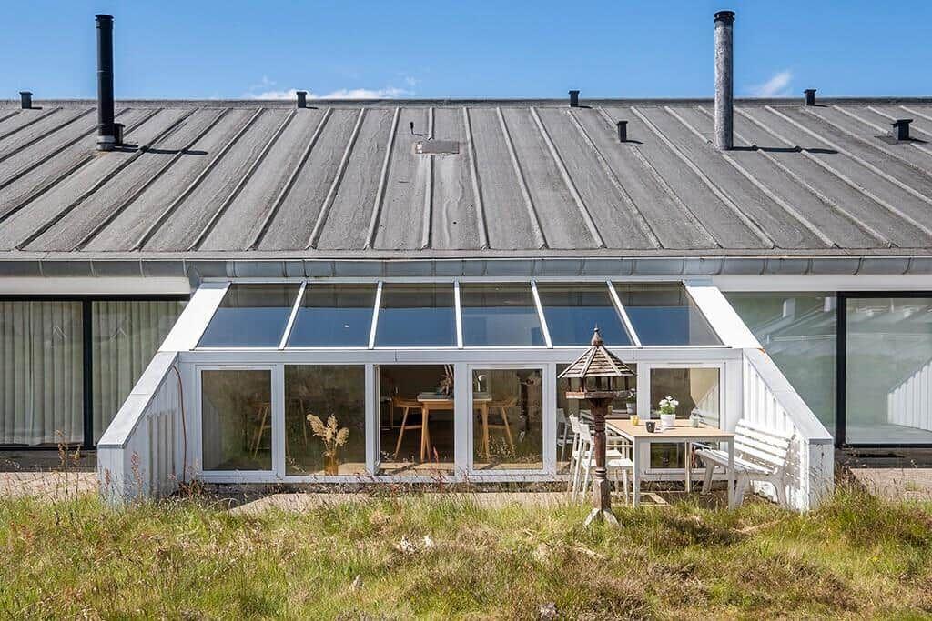 Haus mit Glasveranda, Tisch, Stühle und Vogelhaus im Vorgarten.