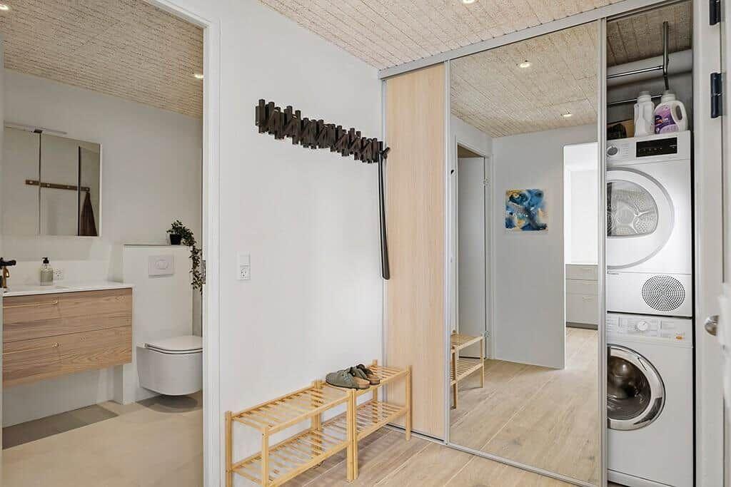 Flur mit Garderobe, Waschmaschine und Badezimmer im Hintergrund.