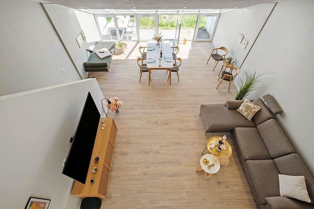Wohn- und Essbereich mit Sofa, Tisch und Blick auf Außenbereich.