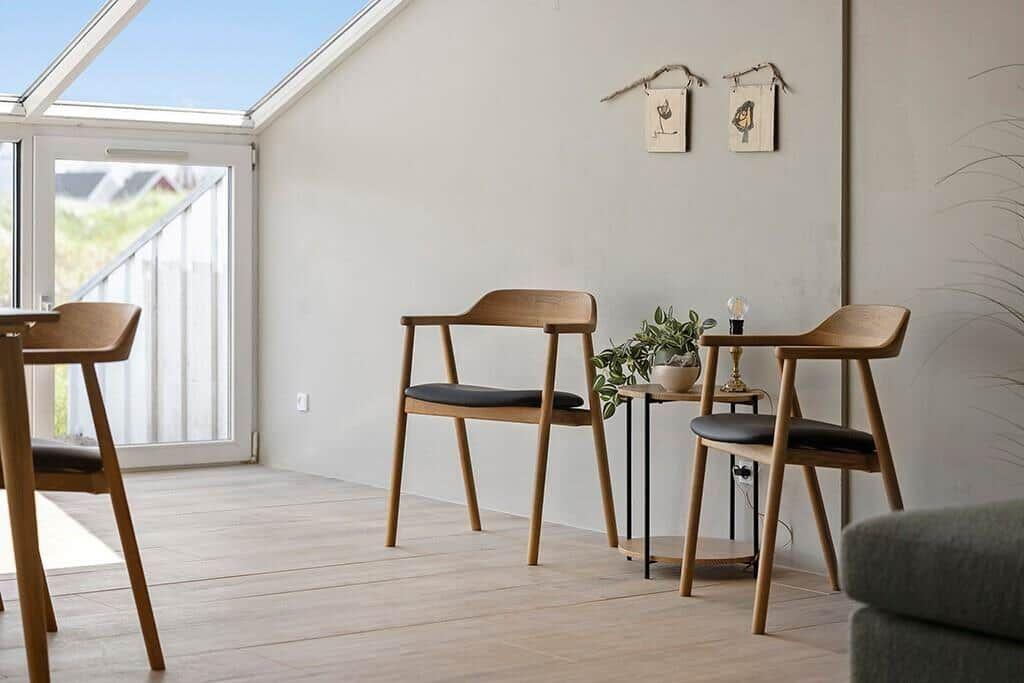 Ein Raum mit Holzstühlen, Tisch und Pflanze unter einem Dachfenster.