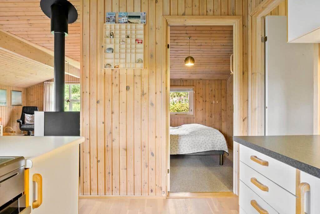 Küche mit Holzwand, Schlafzimmer mit Bett und Fenster