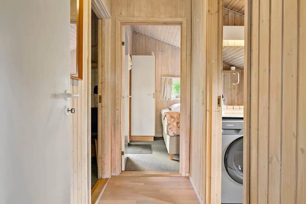Hallenflur mit Blick in Schlafzimmer und Waschraum mit Waschmaschine.