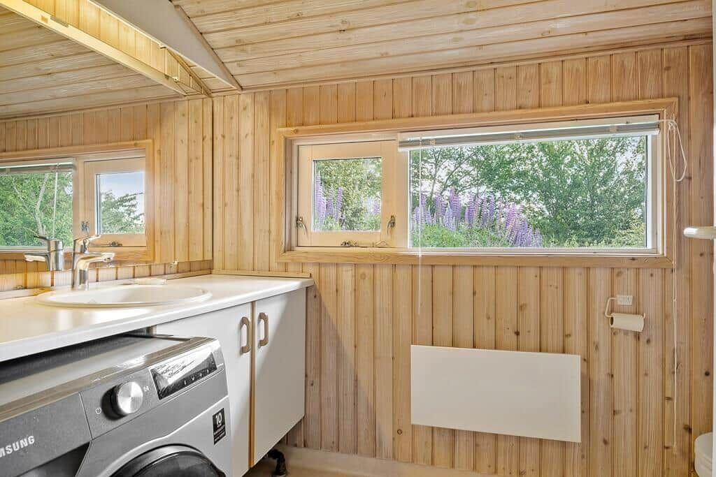 Bad mit Waschmaschine und Fensterblick auf Blumen.