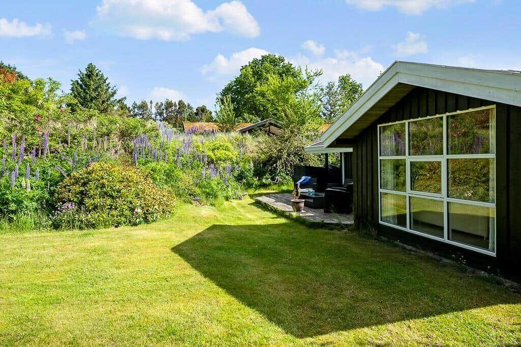 Moderne Villa mit großem Garten und Blumenbeet. Terrasse mit Sitzgelegenheit.