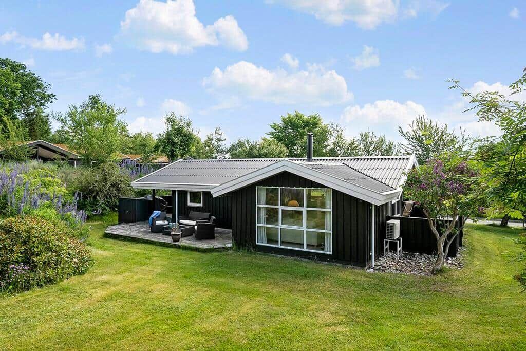 Ein schwarzes Haus mit großer Glasfront und Terrasse im Garten.