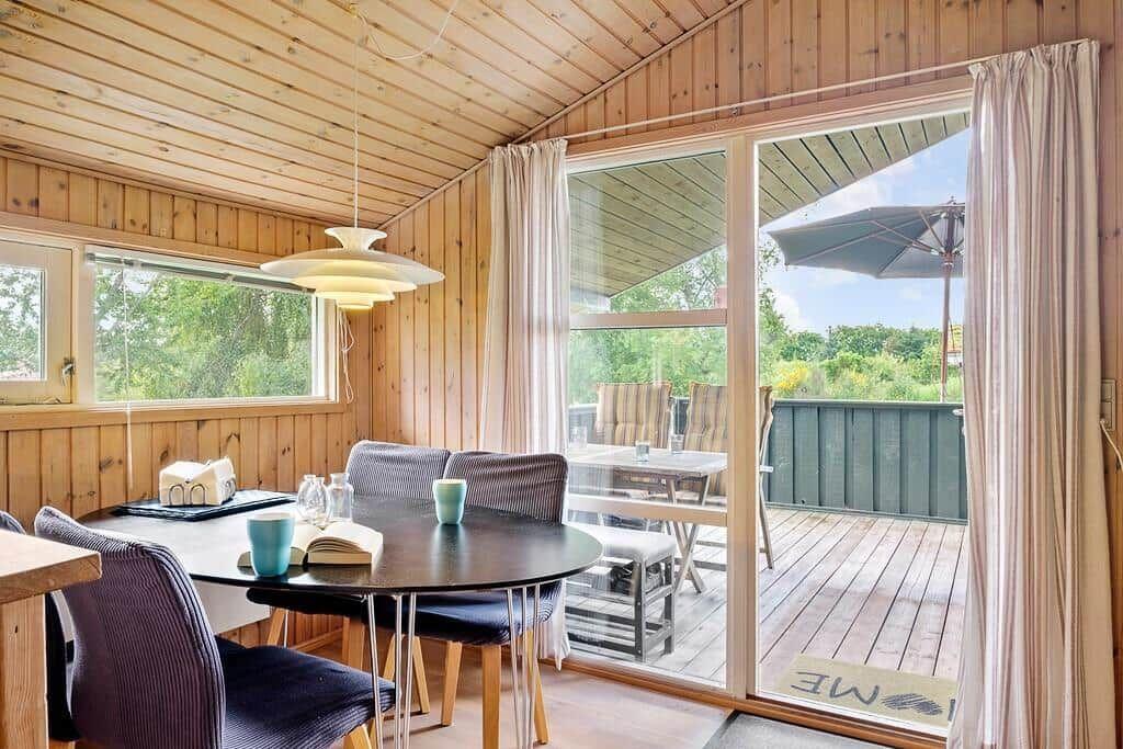 Esszimmer mit Tisch, Stühlen und Blick auf Balkon mit Garten.