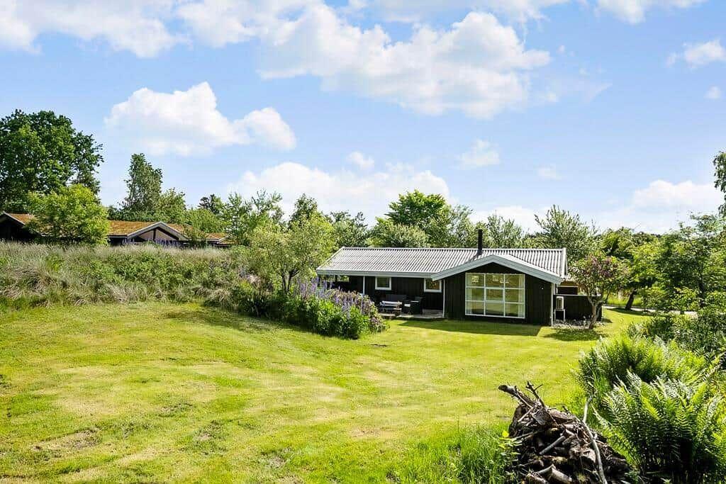 Ein kleines Haus mit grünem Garten und Bäumen unter blauem Himmel.