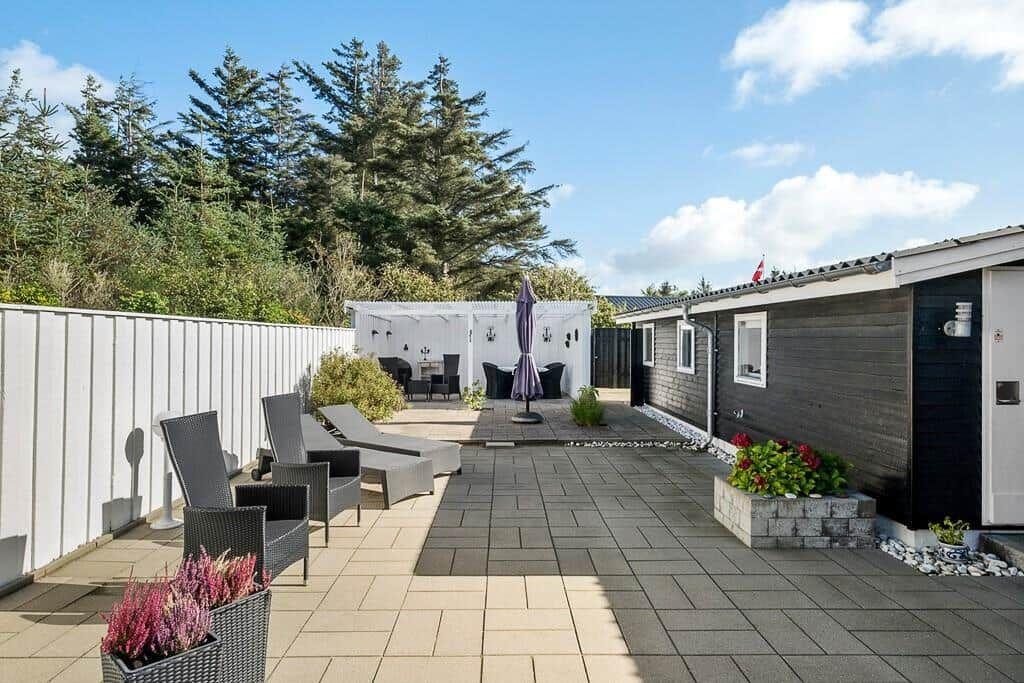 Terrasse mit Liegestühlen, Sonnenschirm und Gartenhaus neben einem Haus.