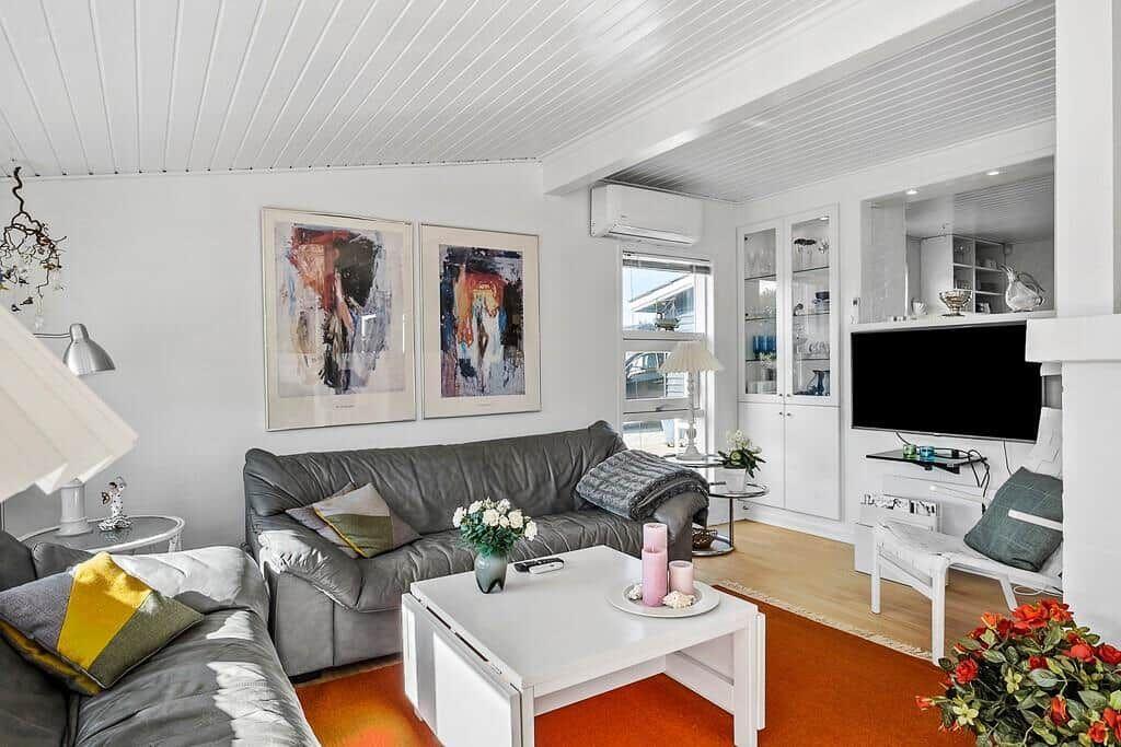 Wohnzimmer mit grauem Sofa, weißen Möbeln und zwei Wandbildern.