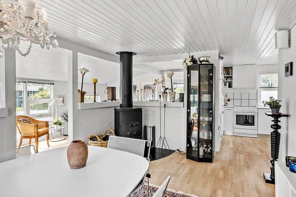 Wohn- und Küchenbereich mit Holzboden, Kamin und Glasvitrine.