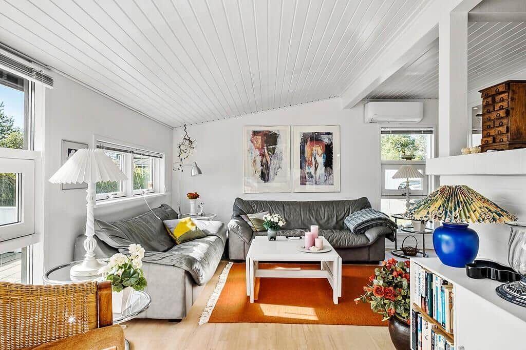 Wohnzimmer mit grauem Sofa, weißem Tisch und orangefarbenem Teppich