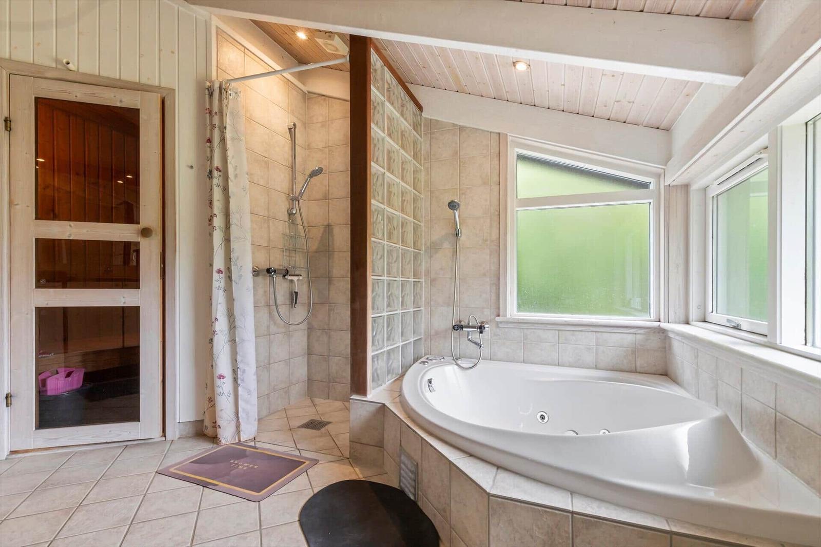 Bath with whirlpool, shower, and sauna. Windows with green glass.