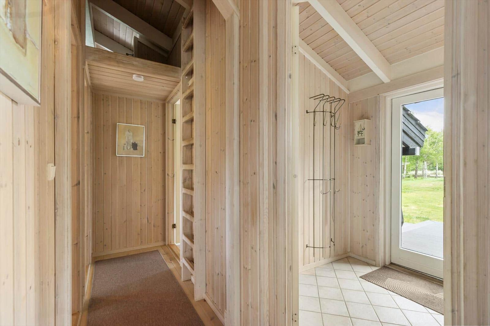Entrance area with wooden walls, coat rack, and door to outdoor area.