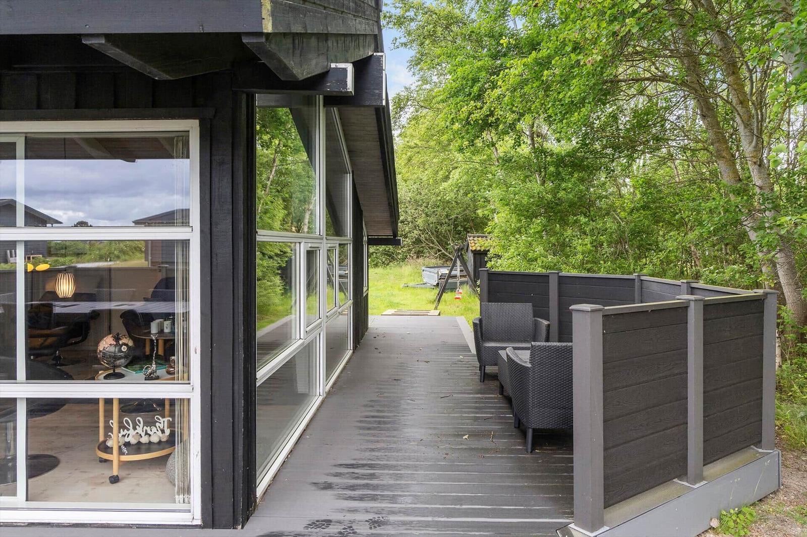 Deck with seating and view into the house. Surrounded by trees and greenery.