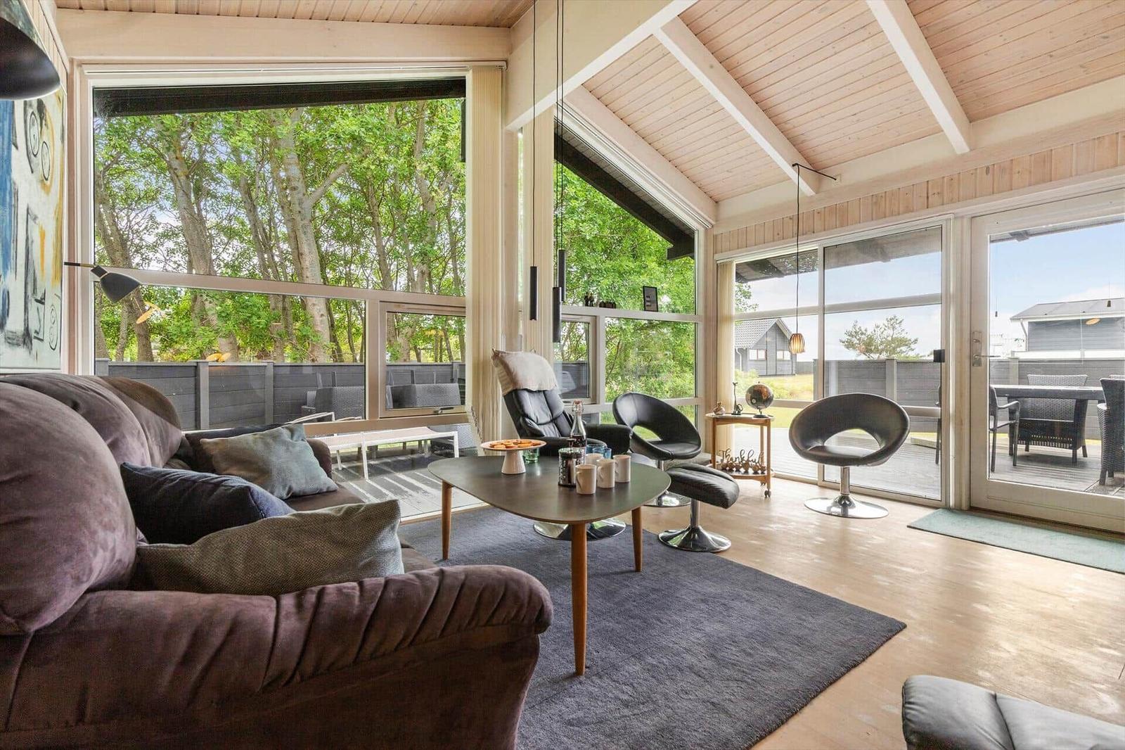 Living room with sofa, chairs, and large window view of trees