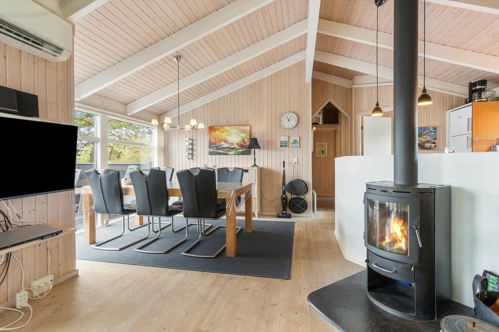 Living and dining area with fireplace, dining table, and large windows.