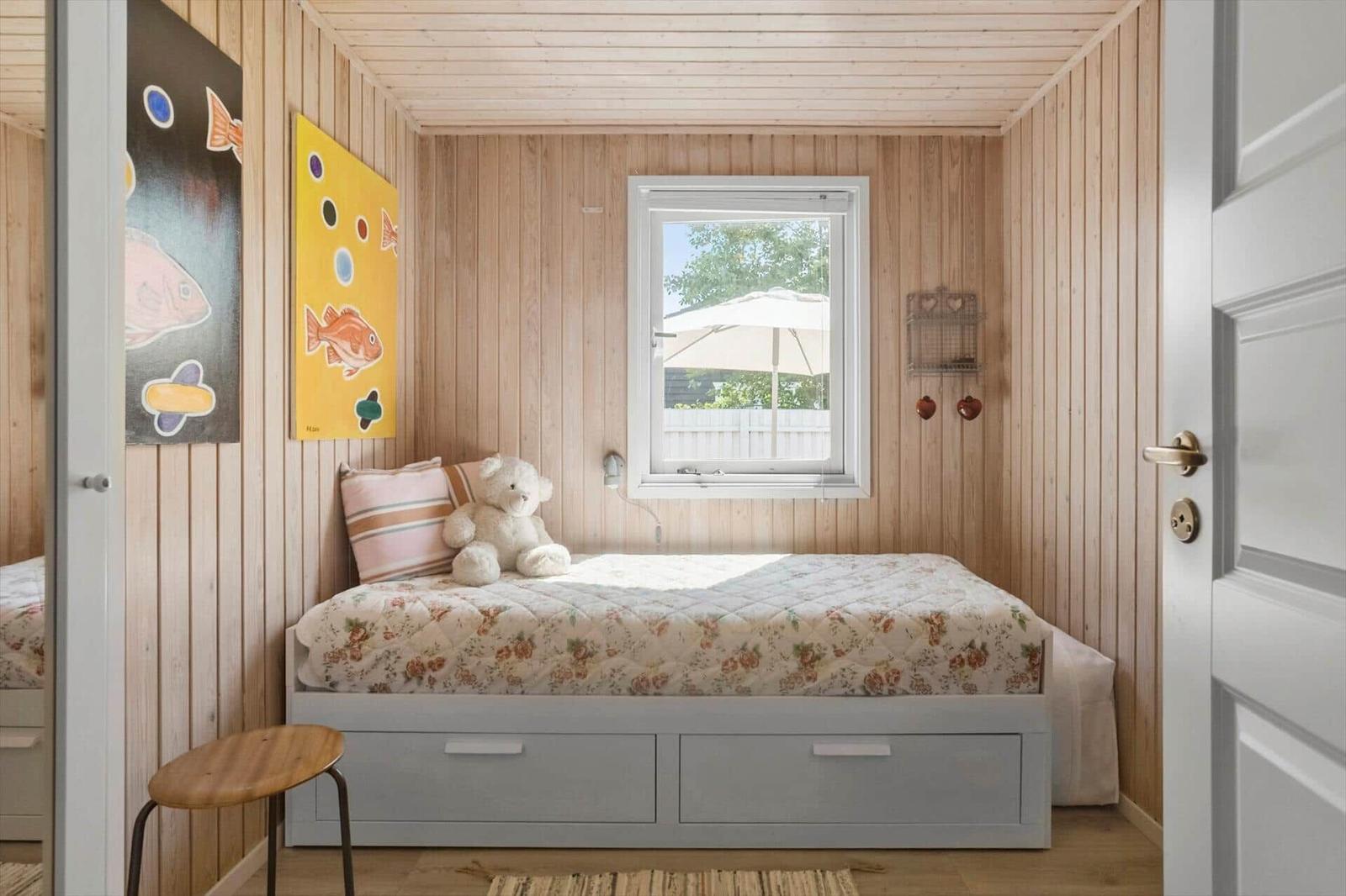 Ein Schlafzimmer mit Holzwänden, einem Bett mit Kissen und einem Teddybären.