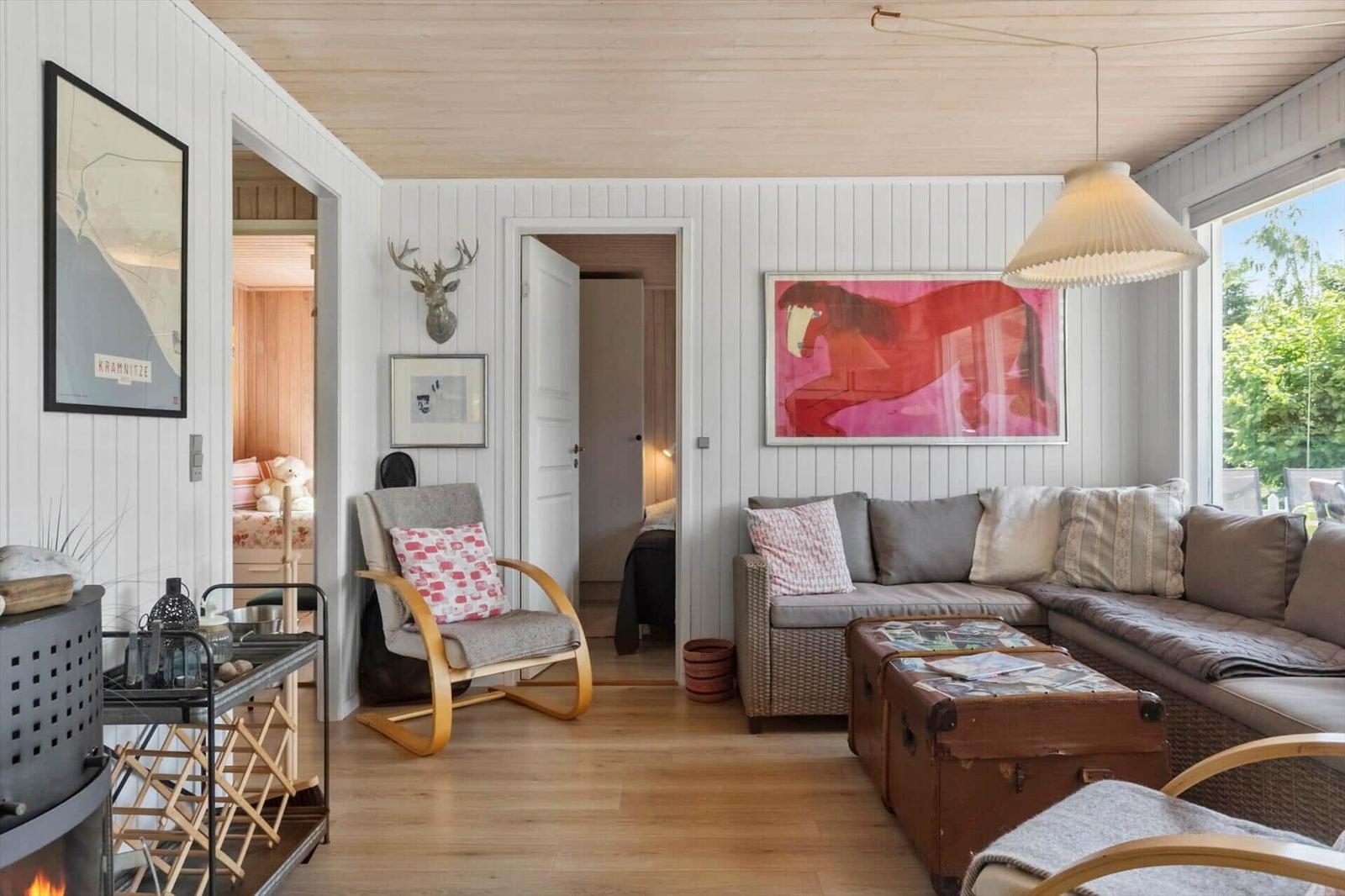 Wohnzimmer mit Sofa, Kamin und Wandbildern. Durchgänge zu Schlafzimmern.