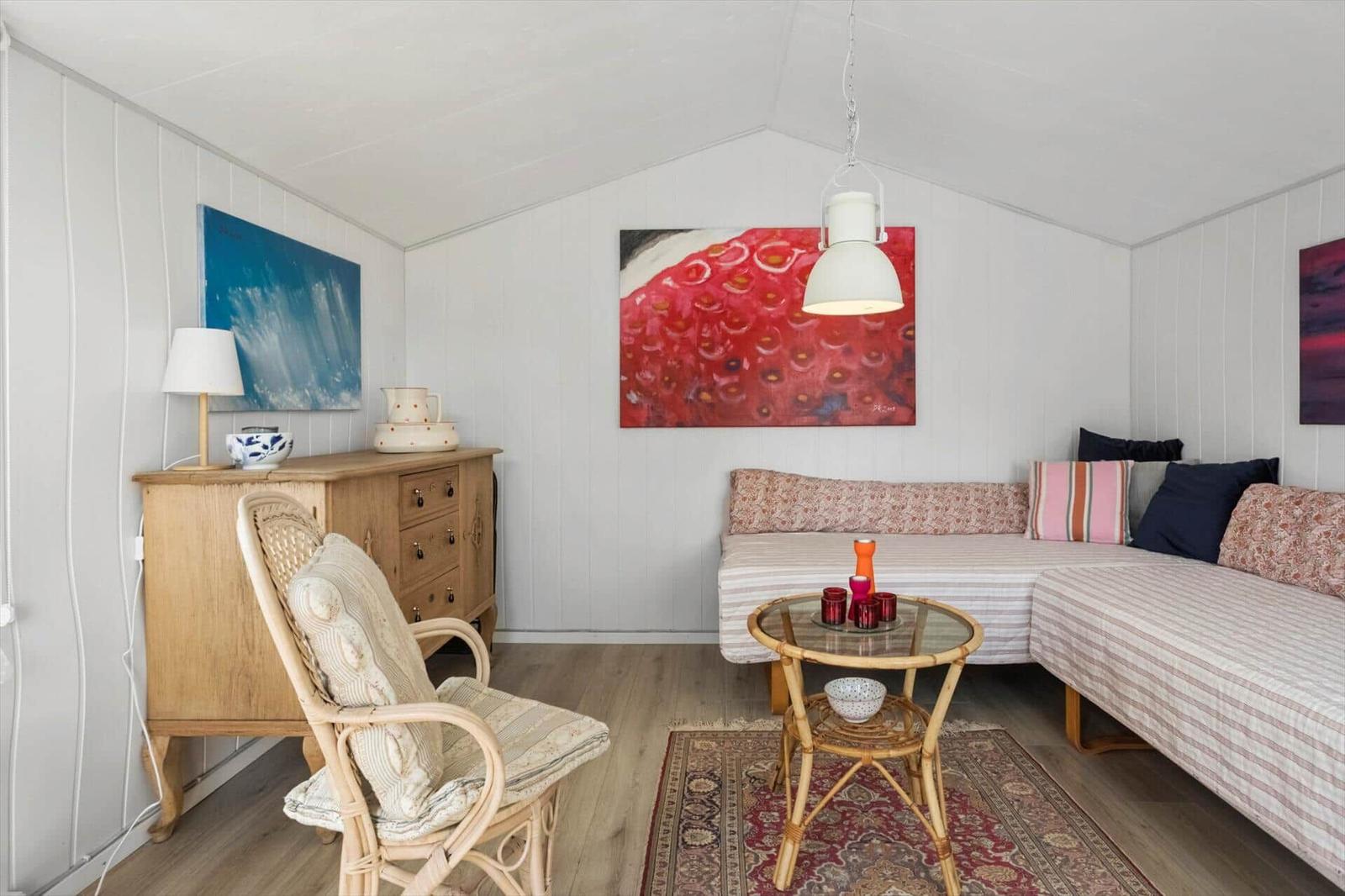Wohnraum mit Sofa, Stuhl, Tisch und Wandbildern.